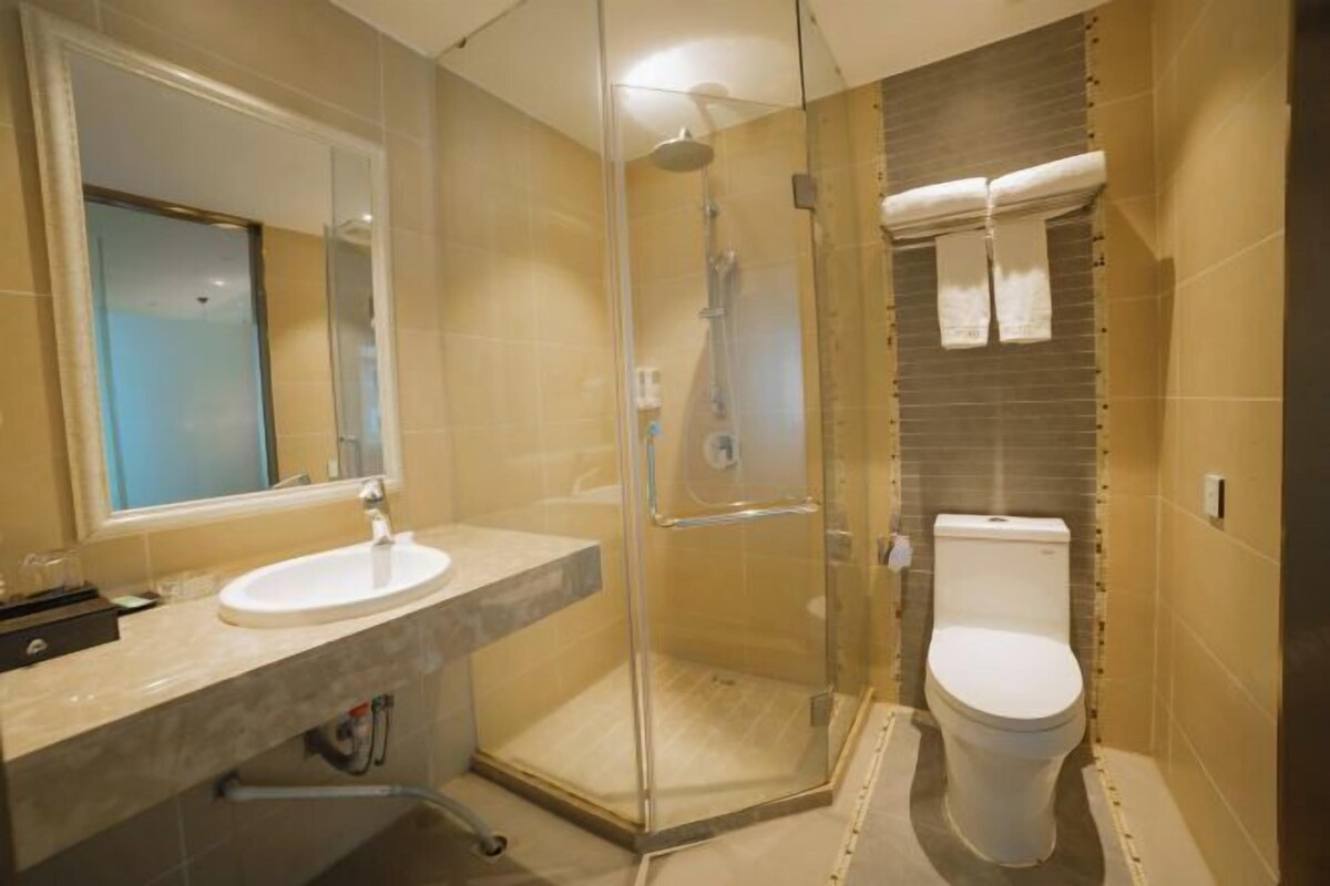 A modern bathroom with a glass-enclosed shower, a white sink, and a toilet.