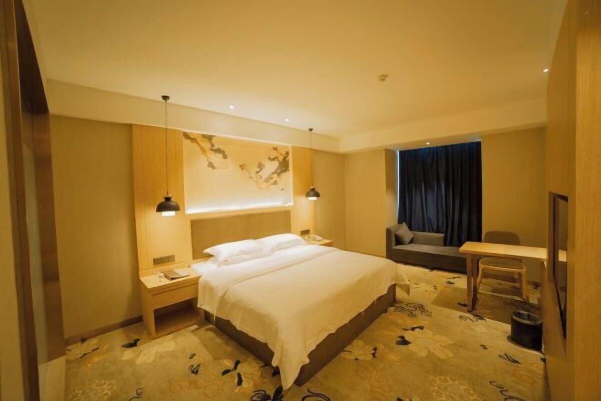 A hotel room with a large bed, bedside tables, a desk, and a chair.