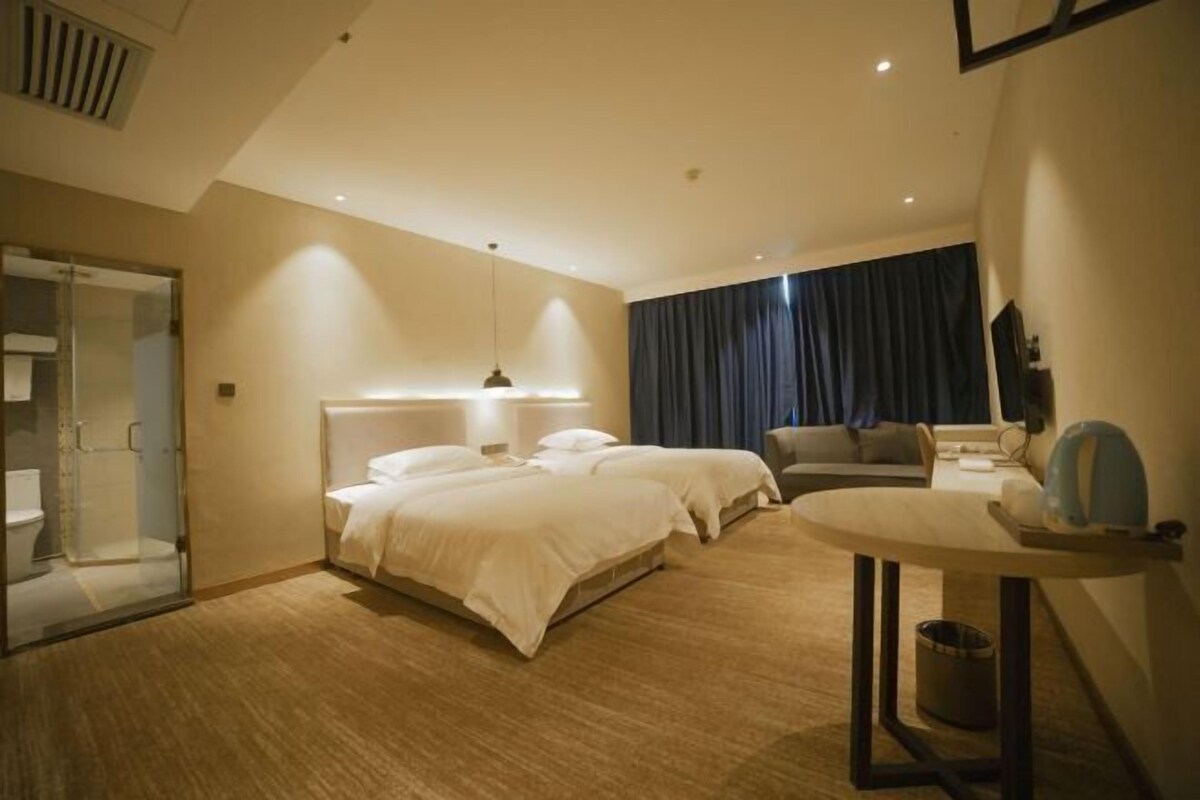 A hotel room with a large bed, a bedside table, a chair, a desk, and a mirror.