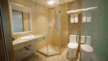 Une salle de bain moderne avec une douche à parois de verre, un lavabo et deux toilettes.