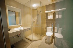 A modern bathroom with a glass-enclosed shower, a sink, and two toilets. - Ruiyi Hotel (Qinzhou)
