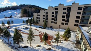 Un patio cubierto de nieve con un edificio que cuenta con varios balcones y una pista de esquí al fondo.