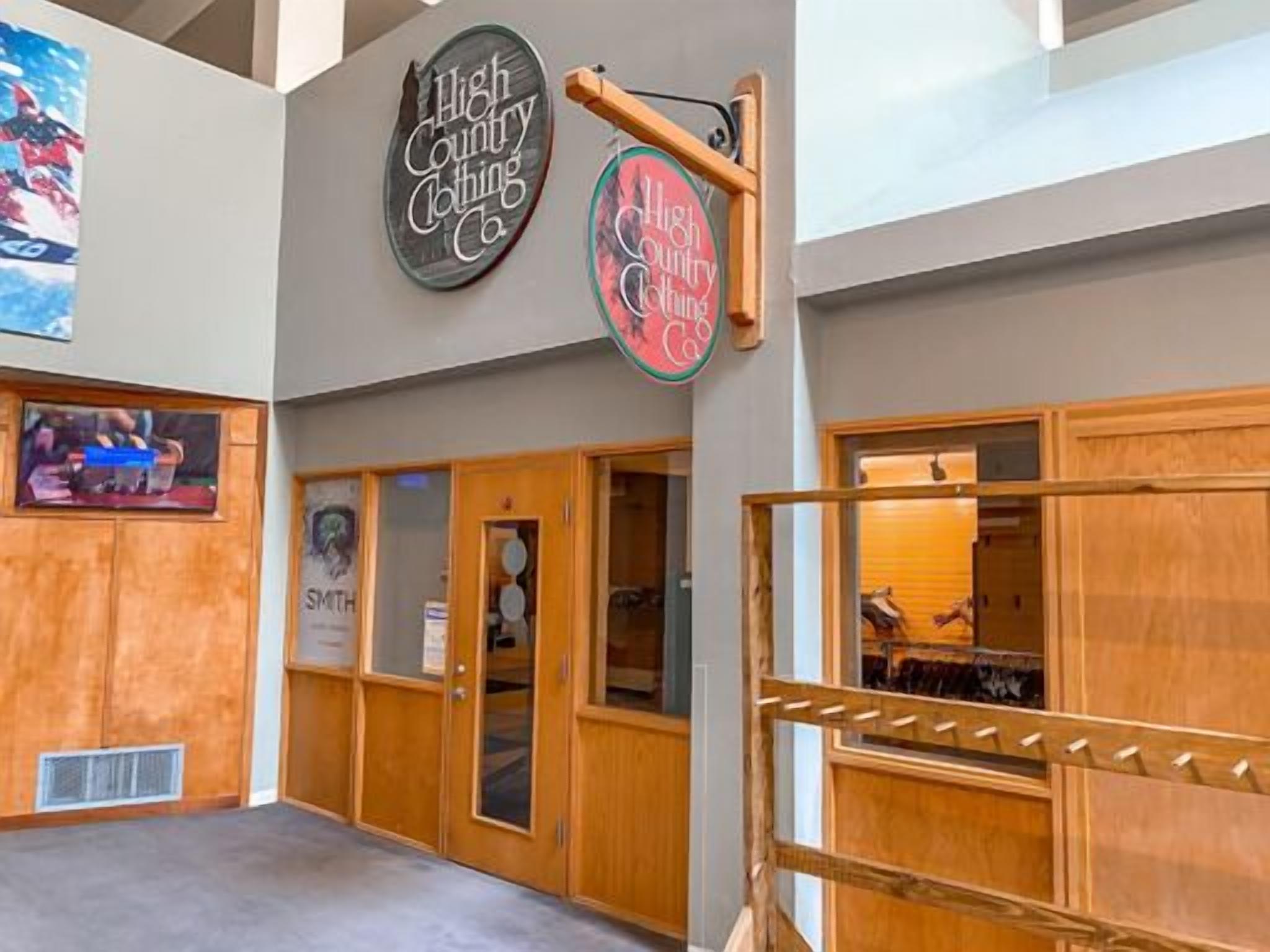 Un hall d’entrée avec des boiseries, une enseigne indiquant « High Country Clothing Co. », et un tableau encadré accroché au mur.