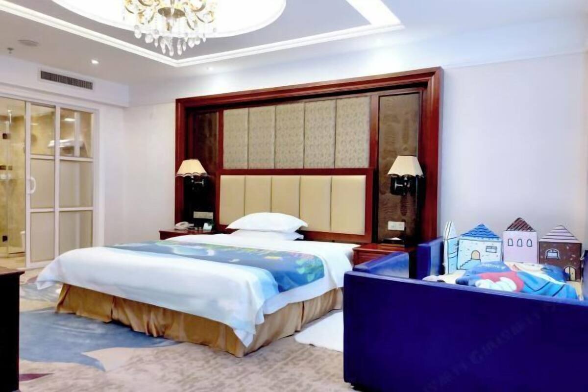 Une chambre d’hôtel avec un grand lit, des lampes de chevet, une armoire et un lustre.