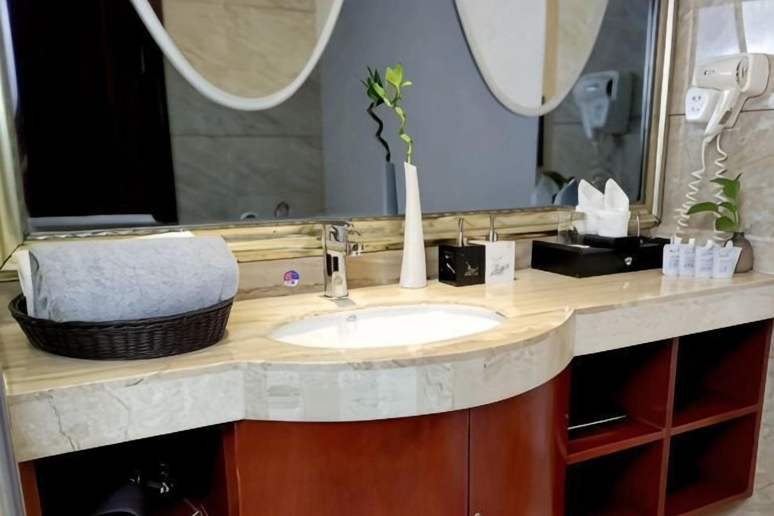 A bathroom with a sink, mirror, towel, and toiletries.