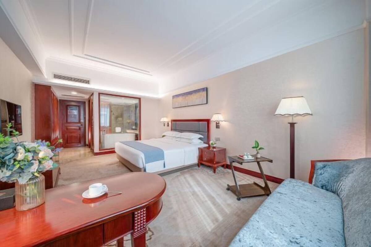 Une chambre d’hôtel comprenant un lit, une table de chevet, une lampe et un bureau avec une chaise.