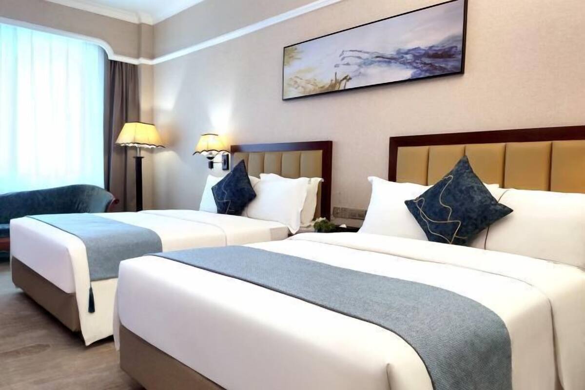 Une chambre d’hôtel avec deux lits, chacun doté d’une tête de lit, de lampes de chevet et d’oreillers décoratifs.