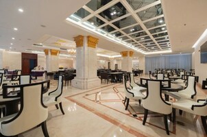 Un comedor amplio con varias mesas y sillas, un techo alto con tragaluces y columnas decorativas.