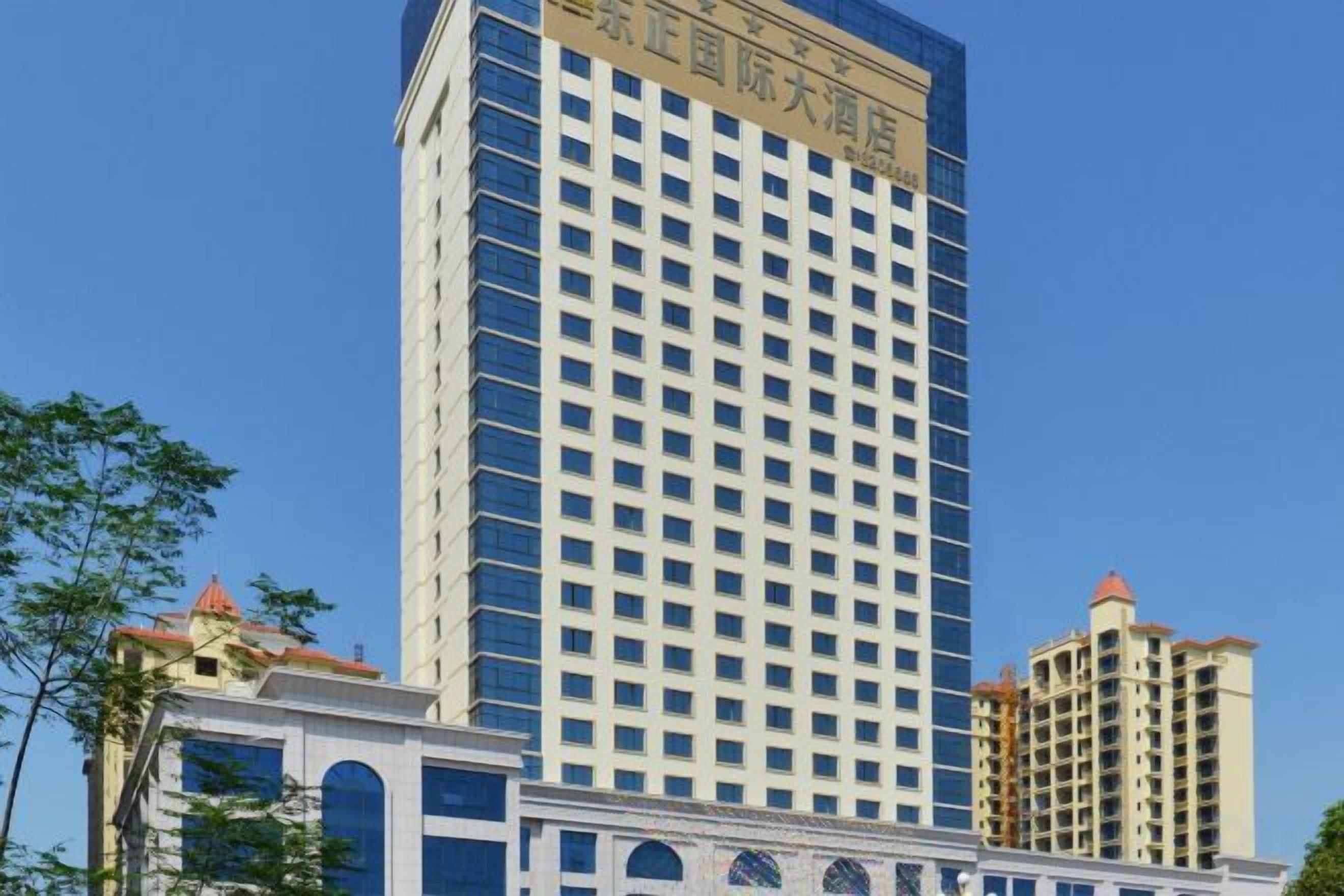 A high-rise hotel with a grid of windows, a flat roof, and a clear blue sky in the background.