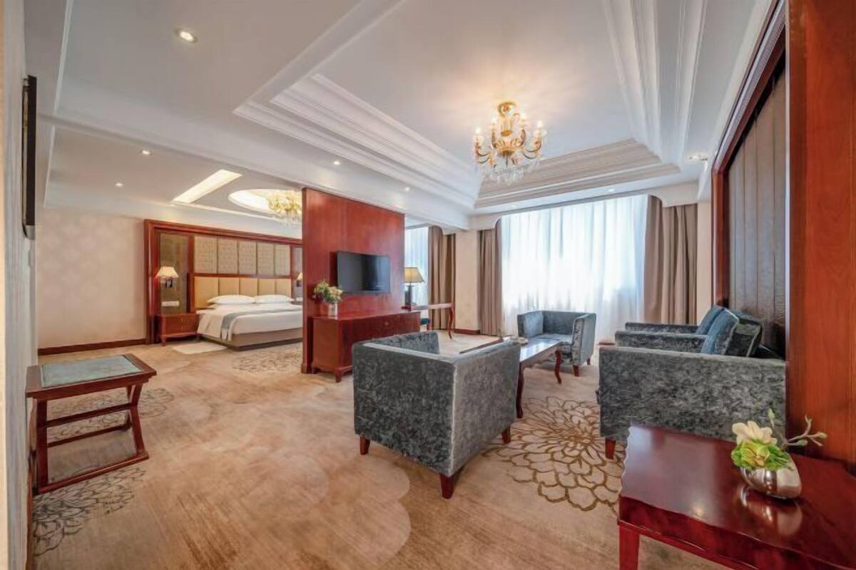 Une chambre d’hôtel avec un lit, un bureau, un canapé et une télévision.