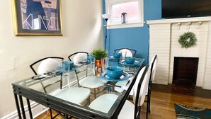 A dining area with a glass table, white chairs, and blue tableware.