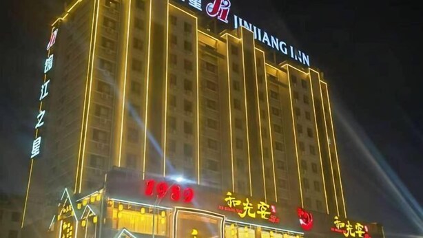 A multi-story hotel with illuminated signage and a prominent 'JINIANG JI' sign on the facade. - Jinjiang Inn (Ulanqab Jining Railway Station Xingfu Road) (Ulanqab)