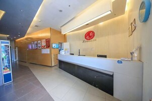 Zona de recepción de un hotel con mostrador, un reloj y una máquina expendedora.
