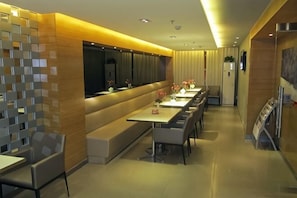 A modern dining area with a long bench, multiple tables, and a decorative wall. - Jinjiang Inn (Ulanqab Jining Railway Station Xingfu Road) (Ulanqab)