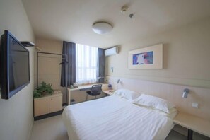 Ein Hotelzimmer mit Bett, Schreibtisch, Stuhl und Fernseher.