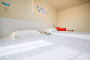 Ein Hotelzimmer mit zwei Betten, einem roten Sessel und einem kleinen Tisch.