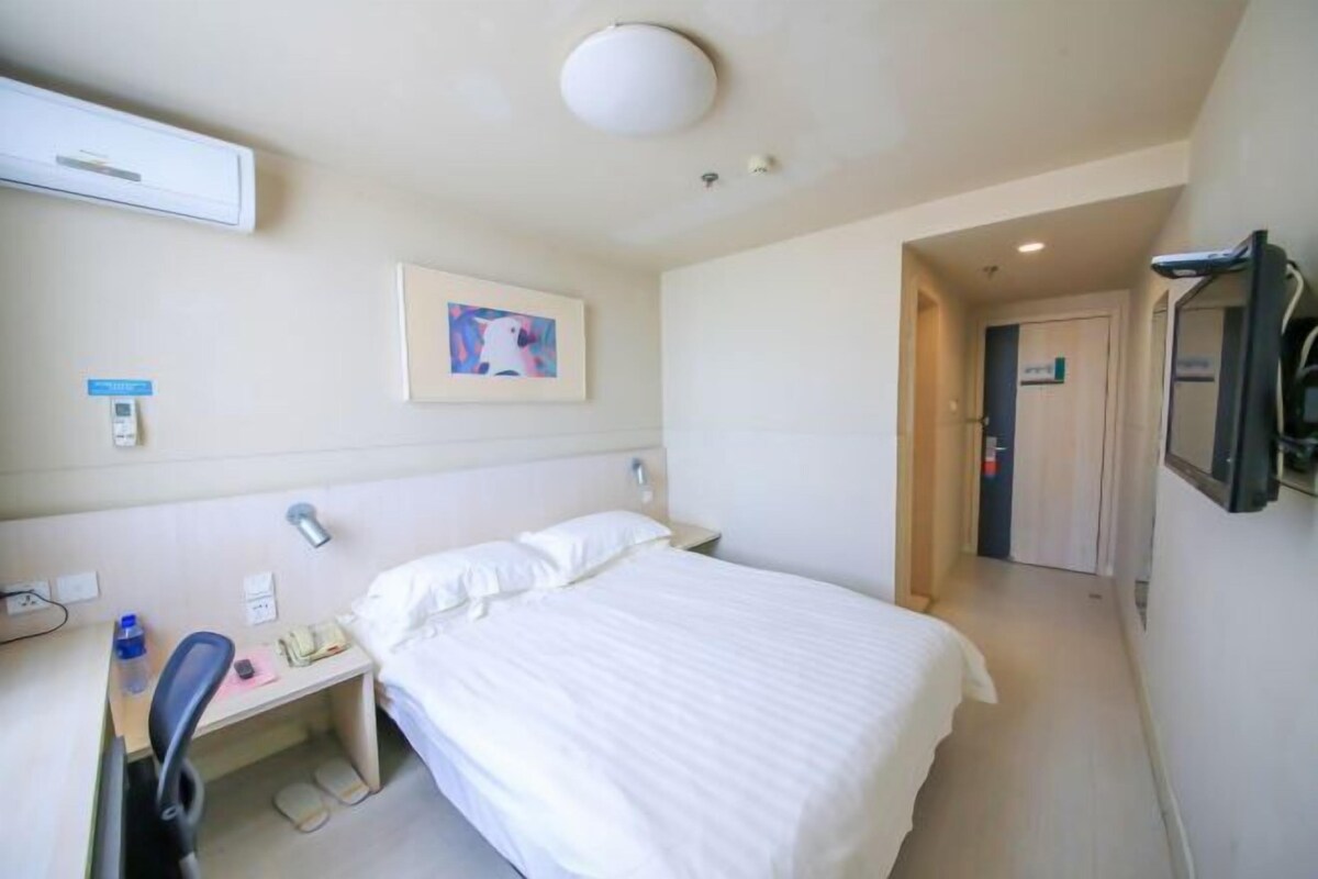 Una habitación de hotel con cama, escritorio, silla y televisor.