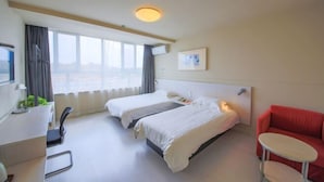 A hotel room with two beds, a desk, a chair, a red couch, and a window with curtains. - Jinjiang Inn (Ulanqab Jining Railway Station Xingfu Road) (Ulanqab)