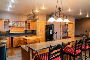 A kitchen with wooden cabinets, a granite countertop, and a central island with bar stools.