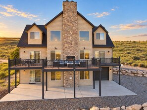 A two-story house with a stone facade, large windows, and a balcony with outdoor furniture.