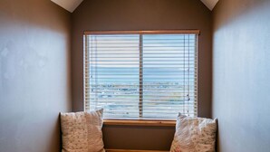 A corner room with a built-in bench, a window with blinds, and a carpeted floor. - Lake Vista Lodge | 5BR Sleeps 24 | Stunning Lake Views, Direct ATV & Snowmobile Trail Access (Garden City)