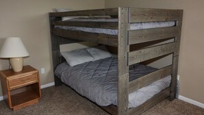 A bunk bed with a wooden frame, a bedside table with a lamp, and a carpeted floor. - Peek' n Peak, Camelot  Loft Condo,  Clymer, NY, 250 Yards to Chair 8, Sleeps 14 (Clymer)