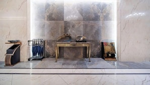 A marble lobby with a central table displaying a decorative item, a coat rack, and a small shelf with a book. - Lingyu International Boutique Hotel (Jinghe)