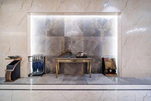 A marble lobby with a central table displaying a decorative item, a coat rack, and a small shelf with a book. - Lingyu International Boutique Hotel (Jinghe)