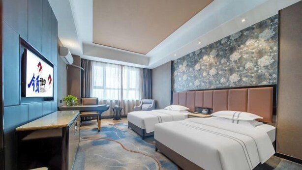A hotel room with a large bed, a desk, a chair, a TV, and a decorative wall. - Lingyu International Boutique Hotel (Jinghe)