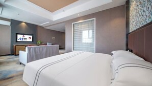 A hotel room with a large bed, a desk, and a television. - Lingyu International Boutique Hotel (Jinghe)
