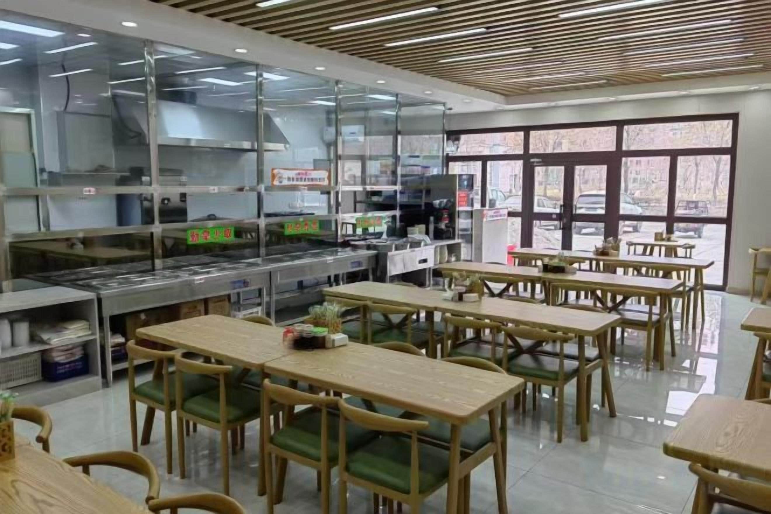 A restaurant with a kitchen area, dining tables, and chairs.