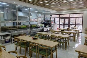 A restaurant with a kitchen area, dining tables, and chairs.