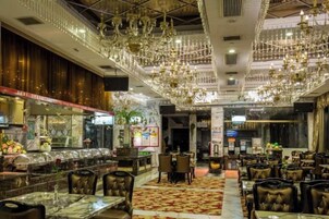 Um restaurante com várias mesas e cadeiras, um bar e um lustre.