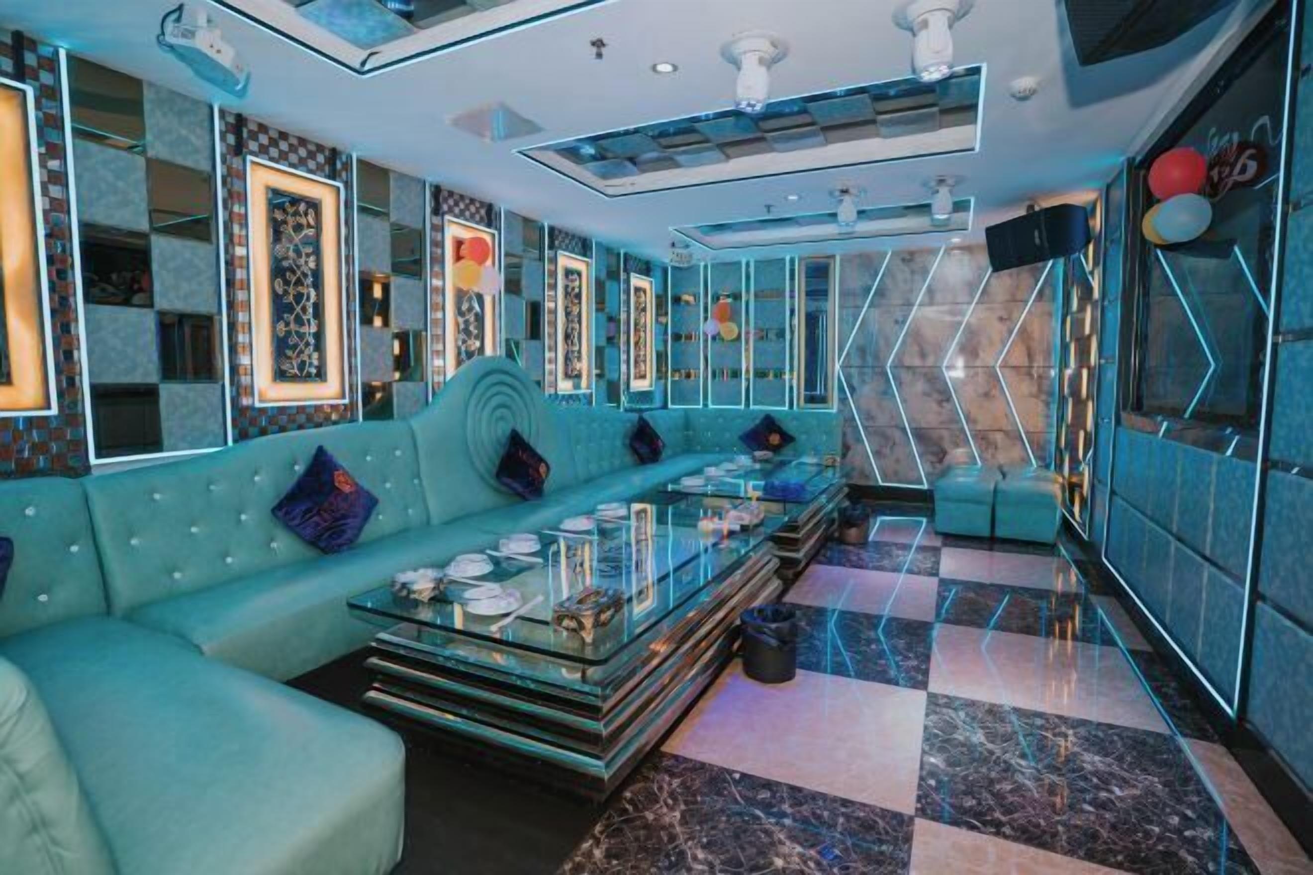 A modern interior with a teal sofa, glass coffee table, and patterned walls.