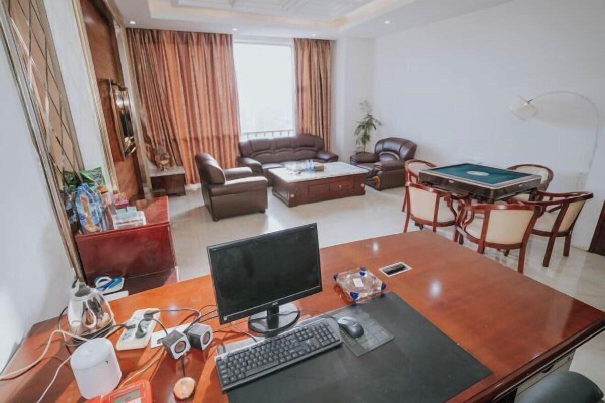 A modern living room with a large desk, computer, and gaming table.