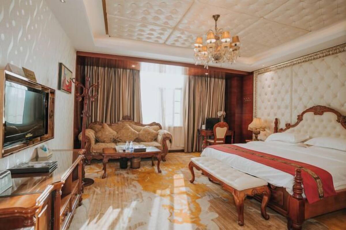 Amplia habitación de hotel con una cama grande, una mesita de centro de madera, un sofá y una televisión.