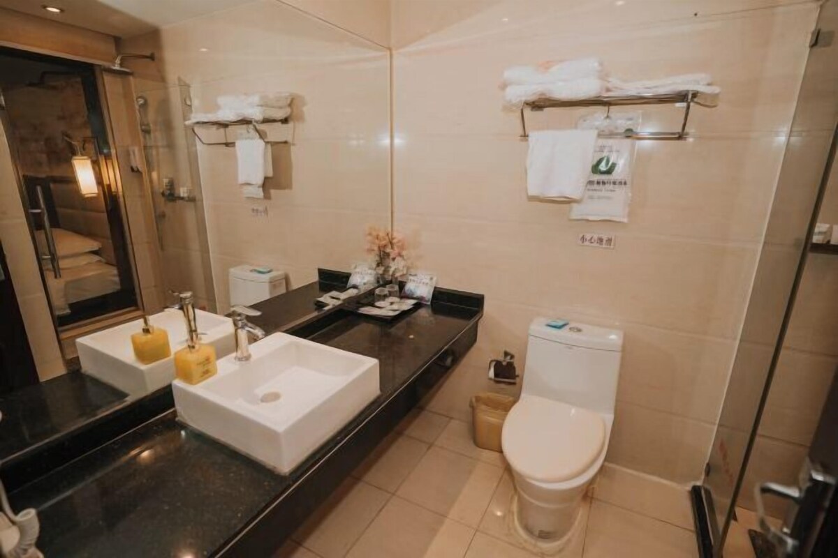 A modern bathroom with a large mirror, two sinks, a toilet, and a shower area.
