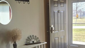 Una habitación con suelo de madera, una consola blanca y una puerta y un ventanal.