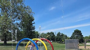 Zona de juegos con agua que incluye tres anillos de colores y un niño jugando.
