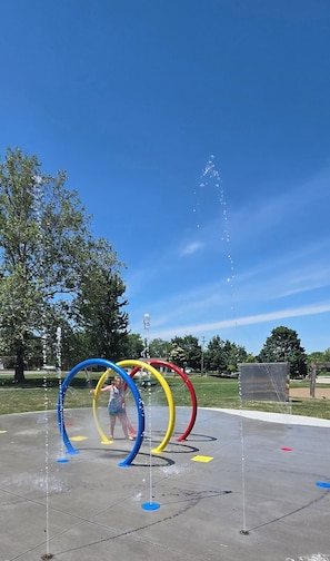 Zona de juegos con agua que incluye tres anillos de colores y un niño jugando.