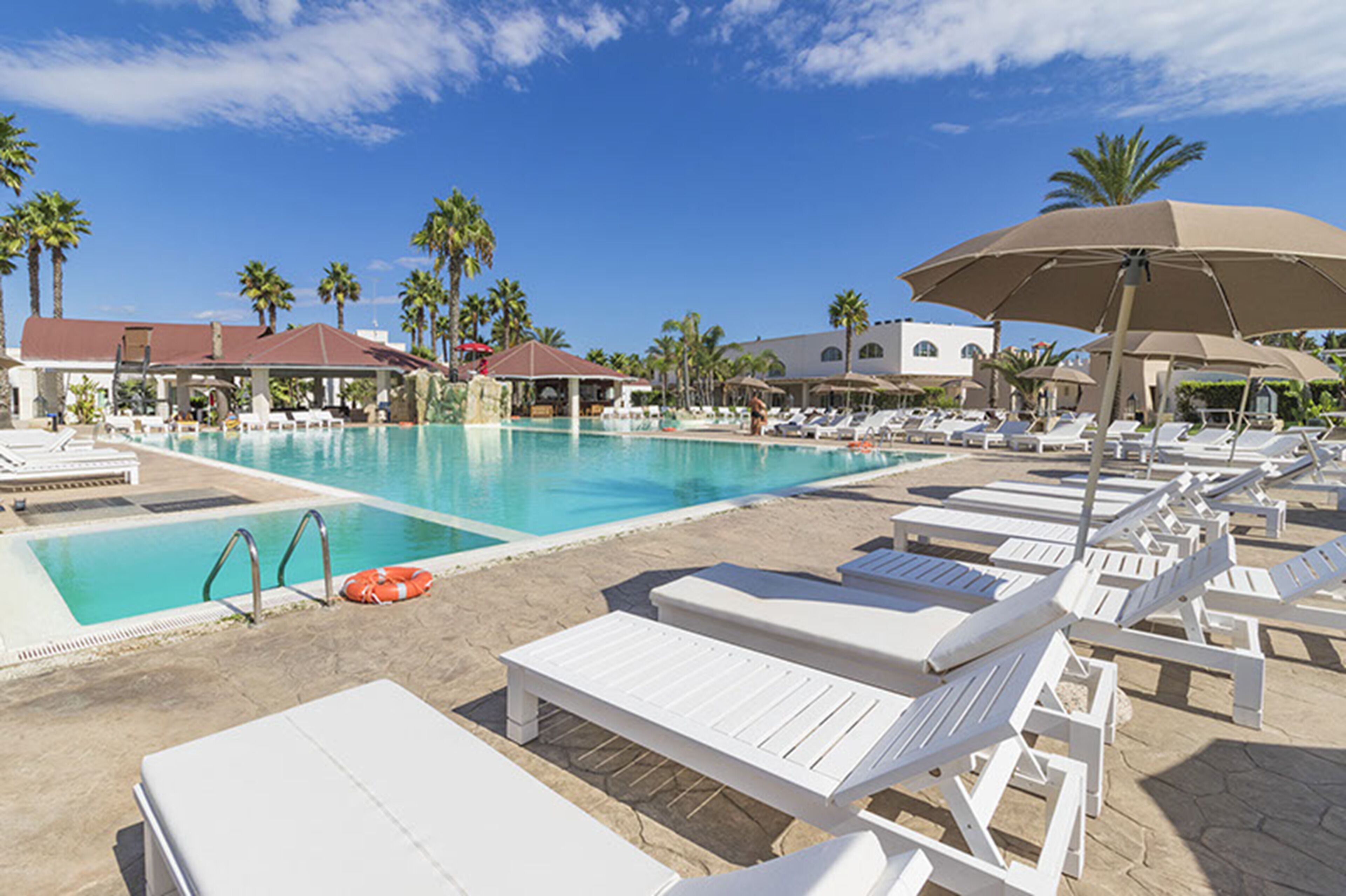 A poolside area with lounge chairs, umbrellas, and a lifebuoy.