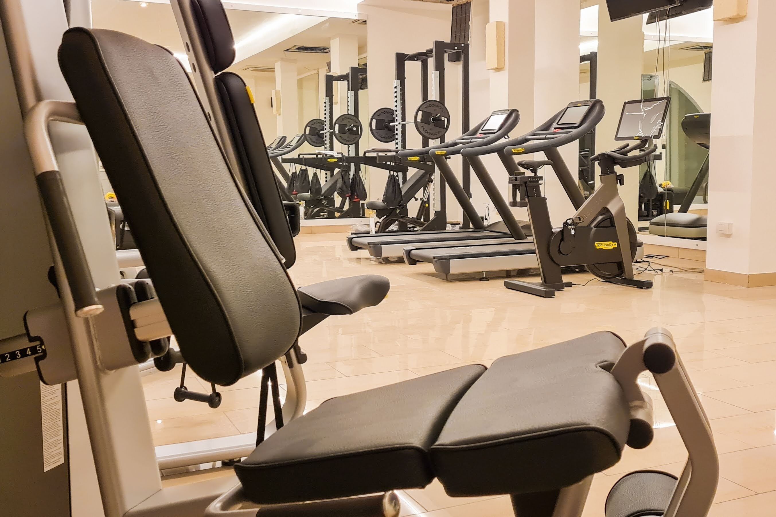 Ein Fitnessstudio mit Trainingsgeräten, darunter Laufbänder und Kraftgeräte.