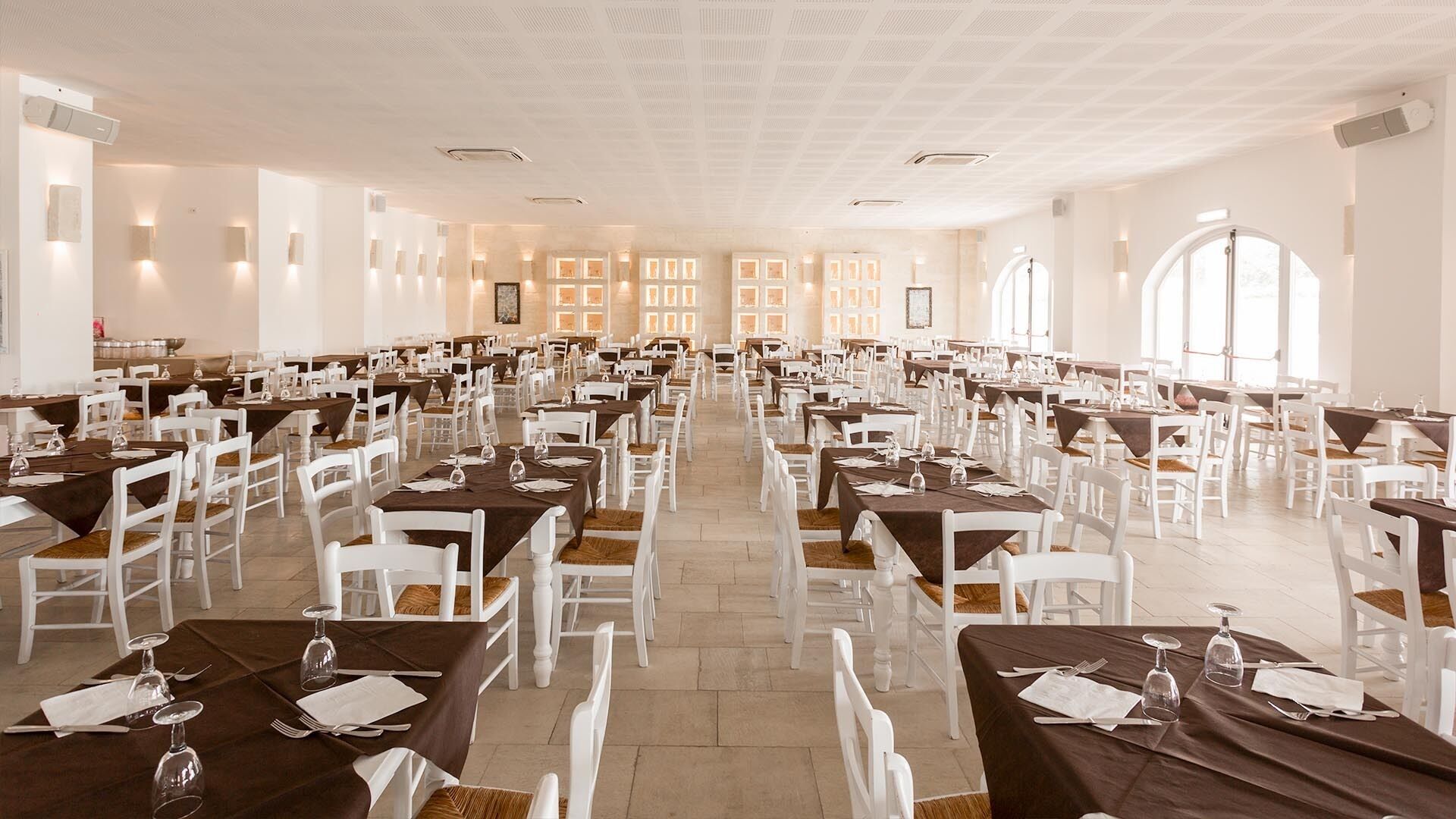 Un comedor amplio con varias mesas y sillas, dispuestas en filas.