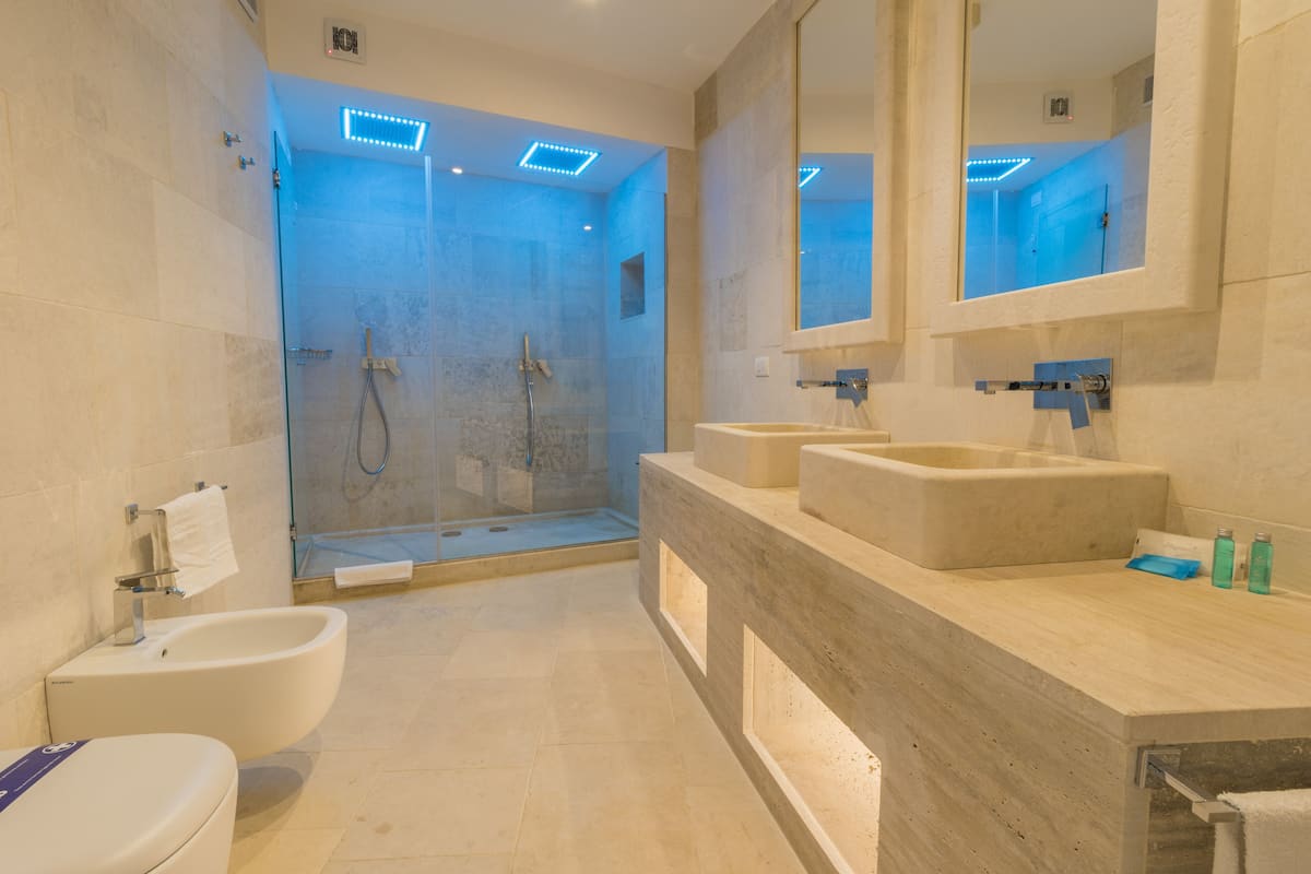 Une salle de bain moderne dotée d’une douche à parois de verre, d’une baignoire sur pieds et d’un grand miroir au-dessus du lavabo.