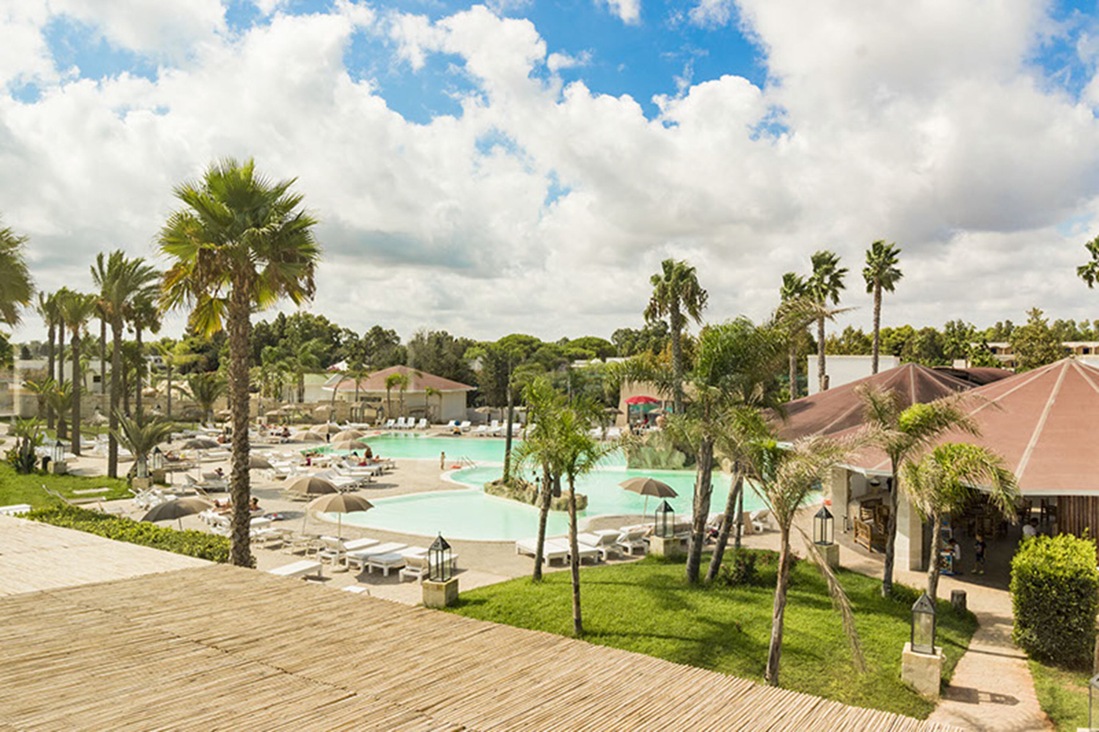 Ein Resort mit großem Pool, Palmen und Liegebereichen.