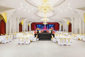A banquet hall with white tables, golden sashes, and a central stage with floral arrangements. - Botai Hotel (Yongqing)