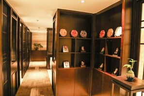 A hallway with wooden floors and walls, featuring a series of shelves with decorative plates and small figurines.