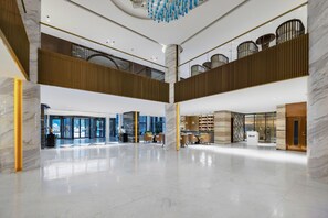 Eine geräumige Lobby mit hoher Decke, Marmorsäulen und einem modernen Kronleuchter.