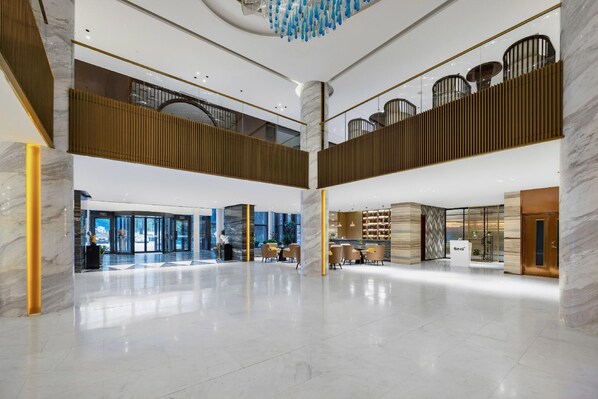 A spacious lobby with a high ceiling, marble columns, and a modern chandelier. - Botai Hotel (Yongqing)