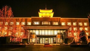Un edificio con tejado al estilo pagoda, una entrada de vidrio amplia e iluminada, y una fachada bien iluminada.